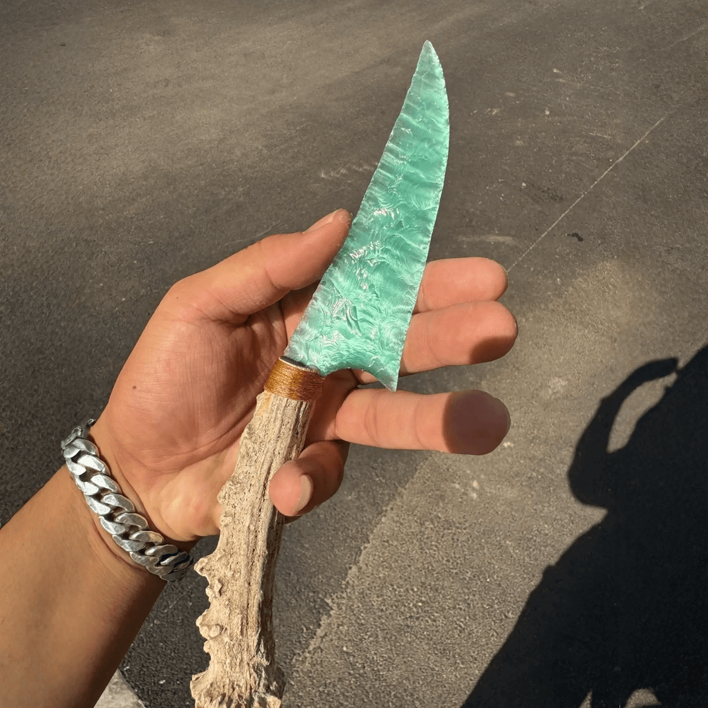 Close-up of seafoam-green stone blade dagger showing flake scars and antler handle