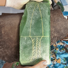 Marking the blade silhouette on a green crystal slab before shaping—outline layout for hand-knapped stone blade