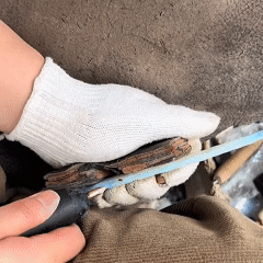 Pressure flaking along the edge of a blue crystal blade blank to create knap scars and crisp geometry