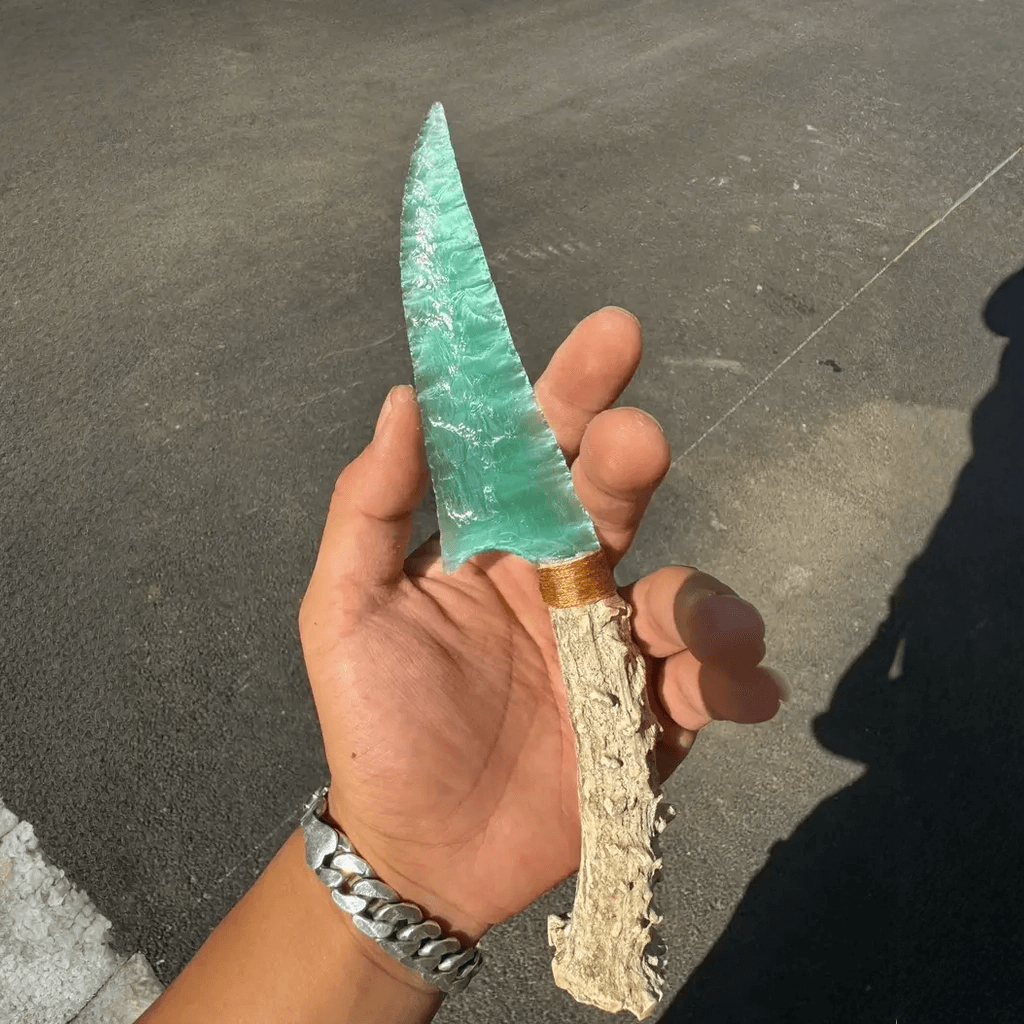 Seafoam-green stone blade dagger in hand, full view of blade and antler handle