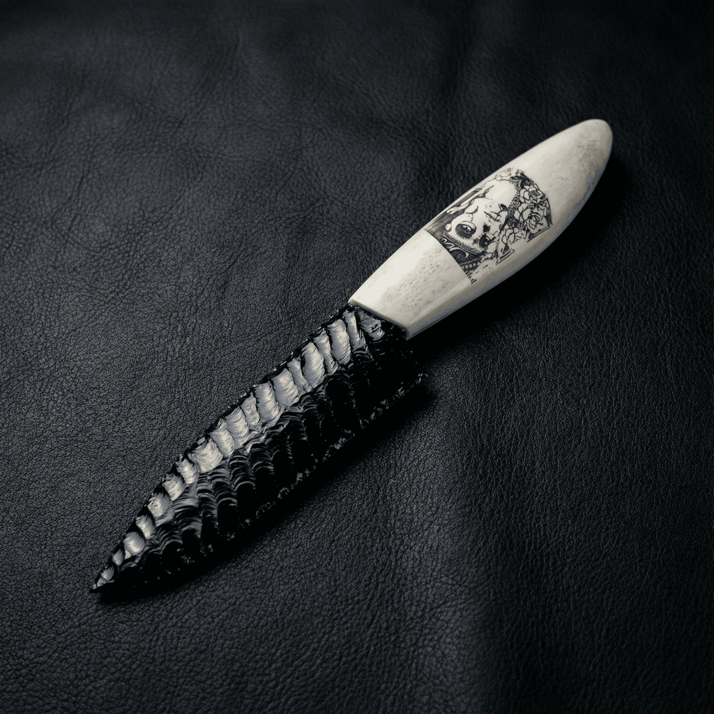 Stoneblade Forge Dagger Stone Blade “Grimwood” — black knapped-style dagger on black leather, featuring a bone-colored handle with skull artwork and glossy flake-scar texture.