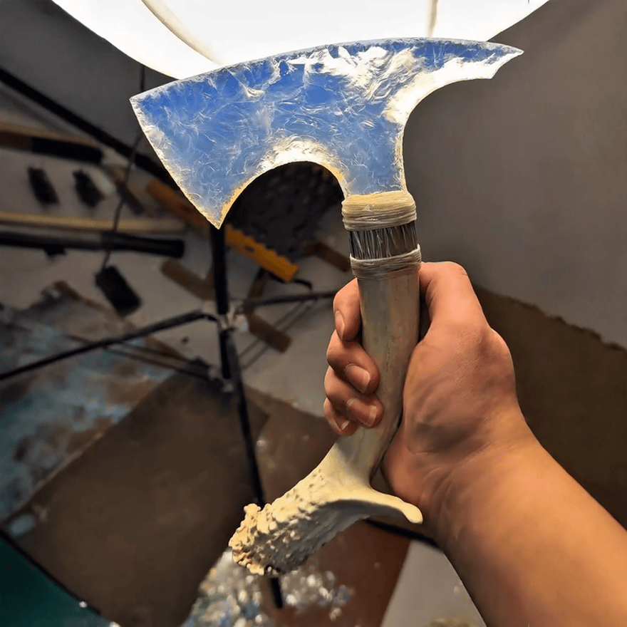 Handheld view of Moonveil transparent opal axe blade showing curved edge and frosted texture