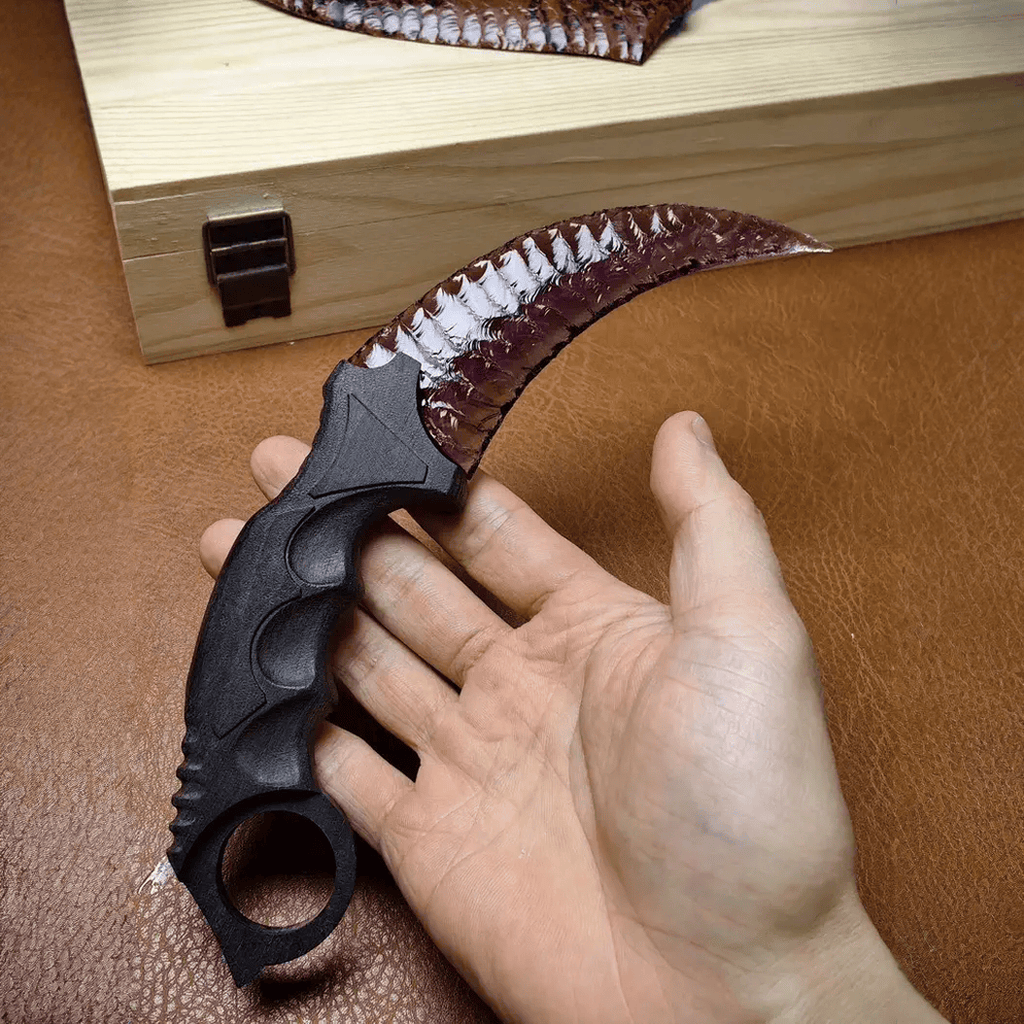 Hand holding deep purple crystal claw stone blade on brown leather workbench, full view