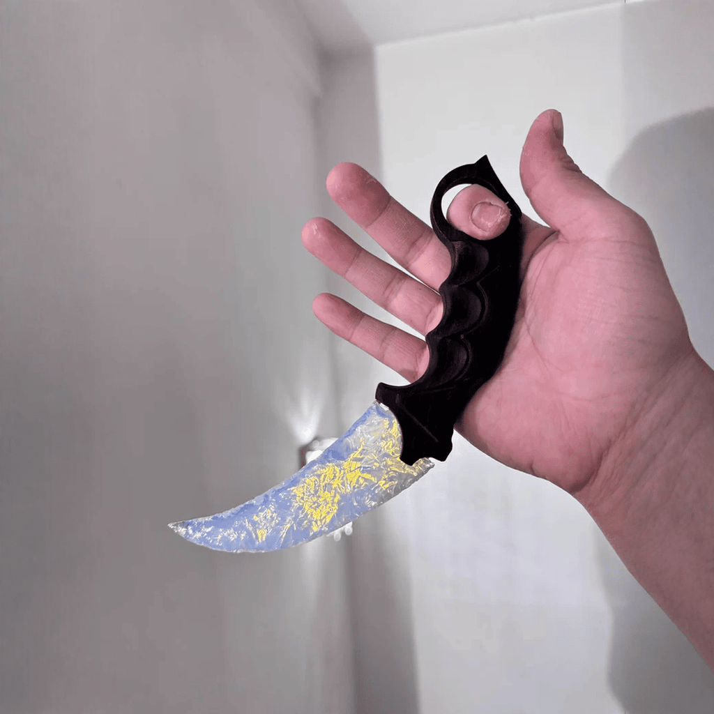 Hand holding opal-blue crystal claw stone blade indoors, side view