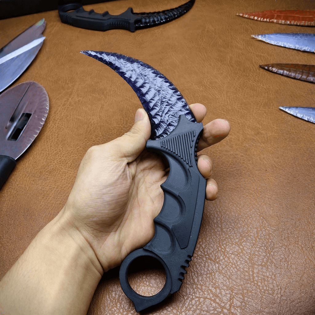 Hand holding black crystal claw stone blade on brown leather workbench, full view