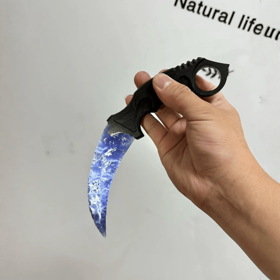 Hand holding blue crystal claw stone blade with ring grip, size reference