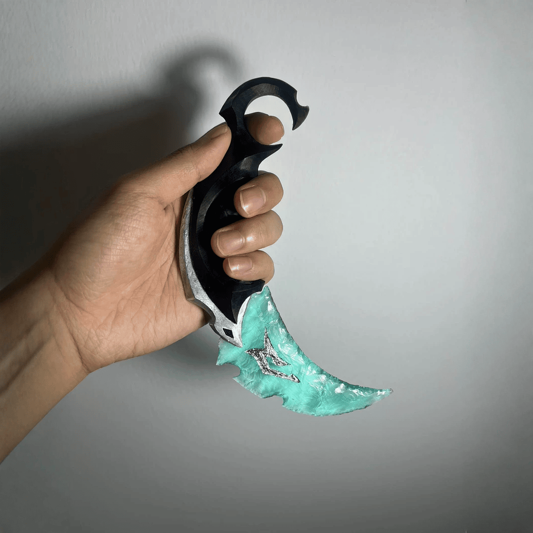 Handheld view of Tidefang teal crystal claw blade with curved profile and ring handle
