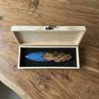 Open wooden gift box display of the blue knapped-style dagger with carved wood handle on a wooden tabletop (Oblivion).