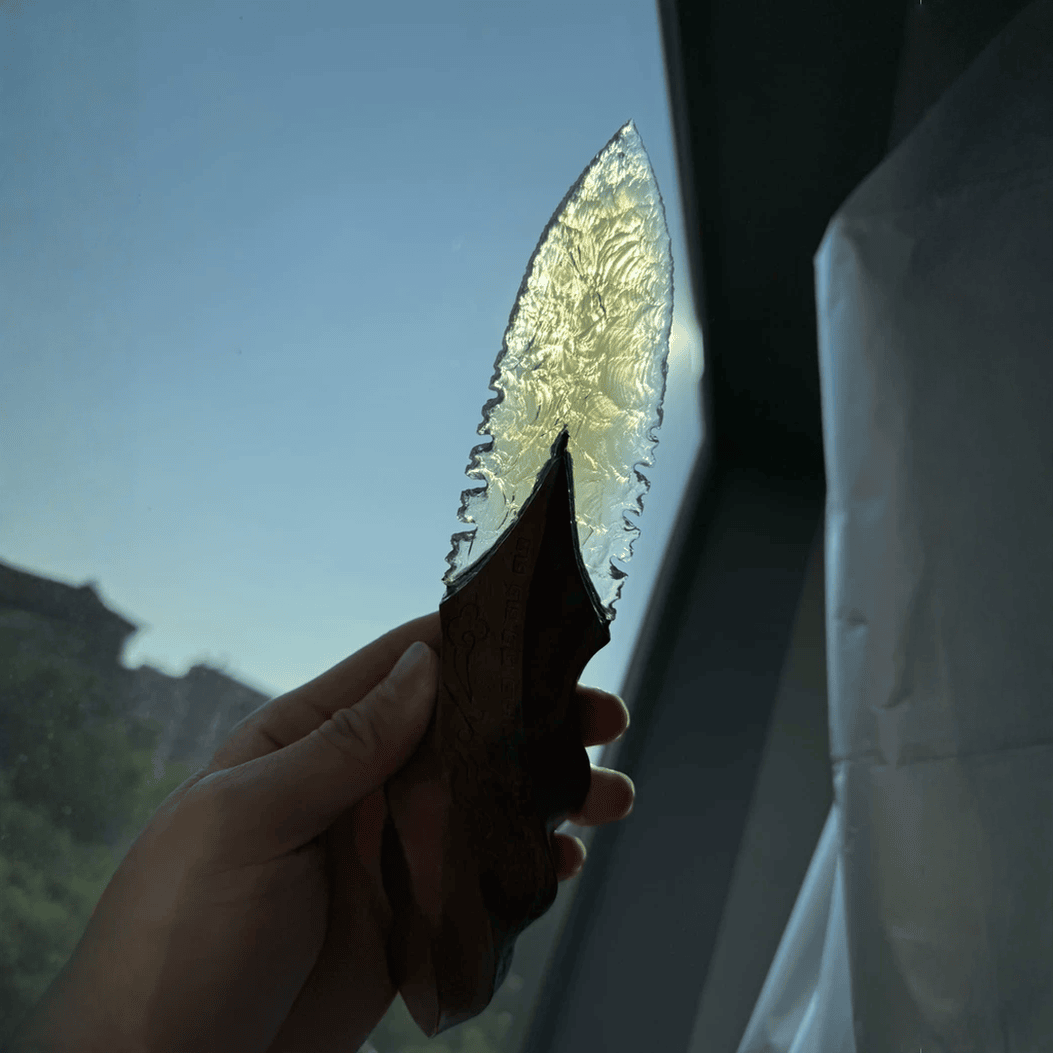 Backlit view highlighting the translucent knapped-style blade texture and the carved handle silhouette (Oblivion dagger).