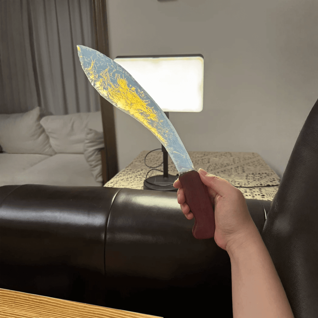 Auroraflare opal curved blade in hand with backlight showing warm golden glow through the edge