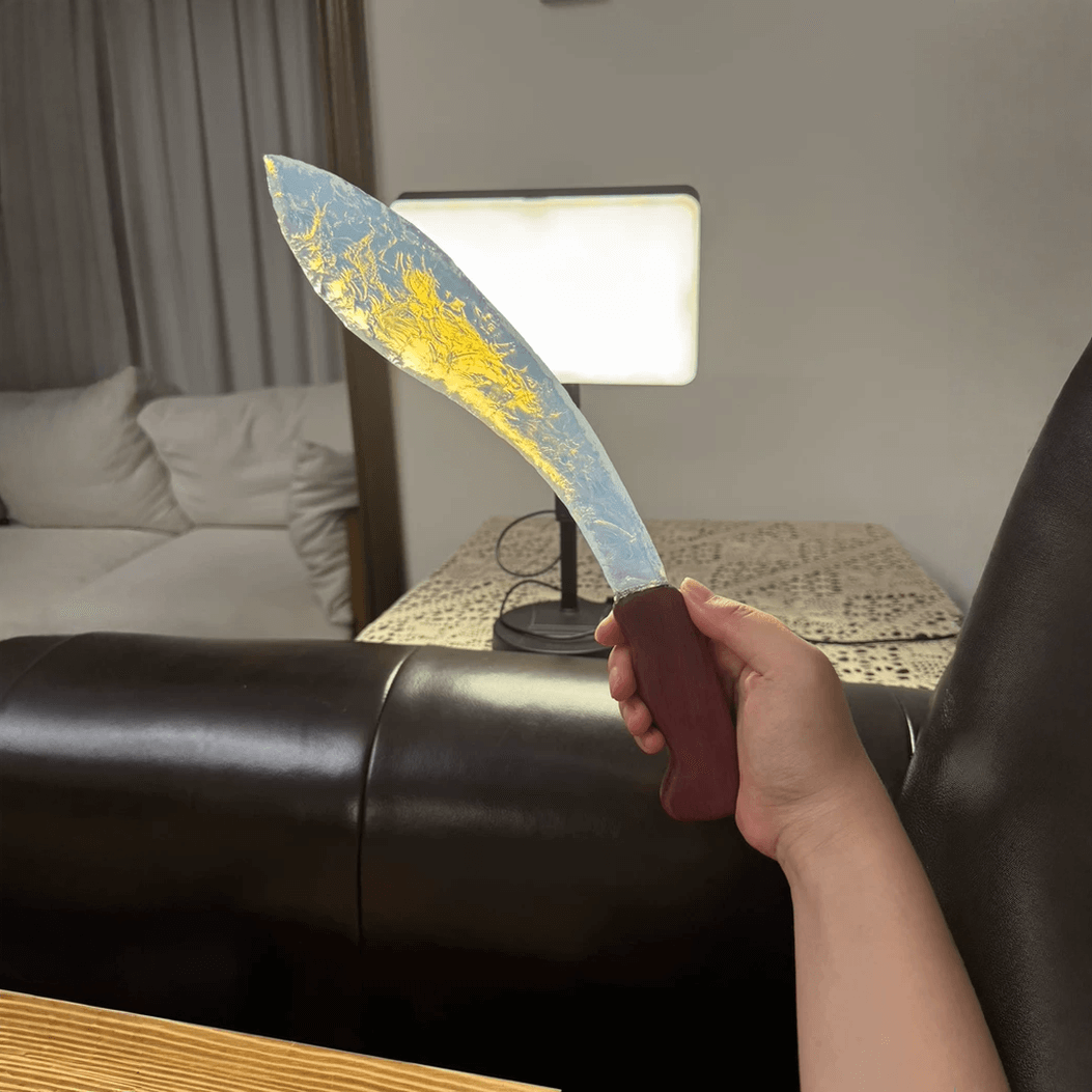 Auroraflare opal curved blade in hand with backlight showing warm golden glow through the edge