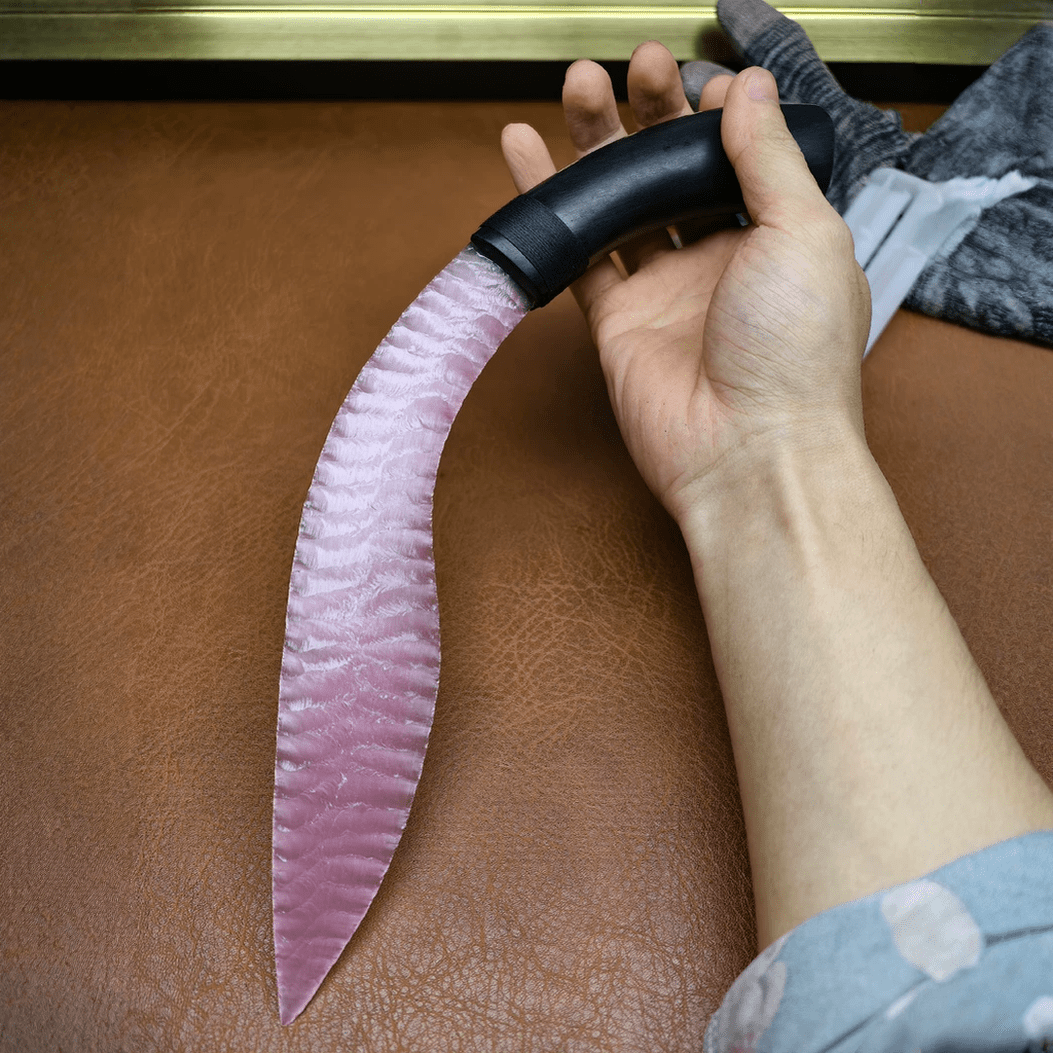 Nightbloom rose quartz curved blade in hand showing knapped wave texture and black handle