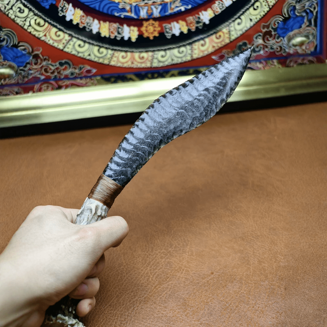 Close-up of Stagshade silver sheen obsidian curved blade highlighting bold knapped wave texture and primitive styling