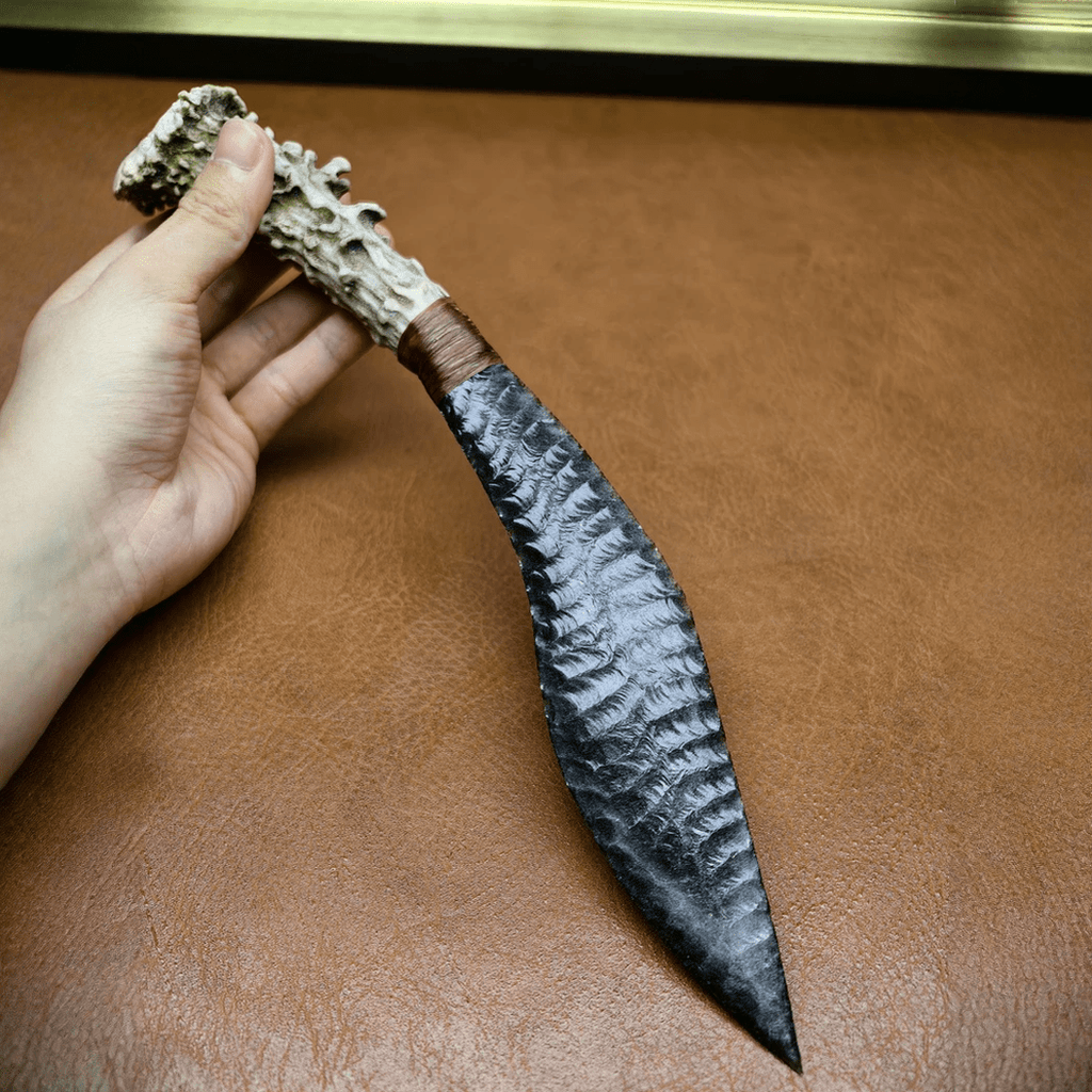 Handheld Stagshade curved obsidian stone blade showing silver sheen knapped texture and antler handle