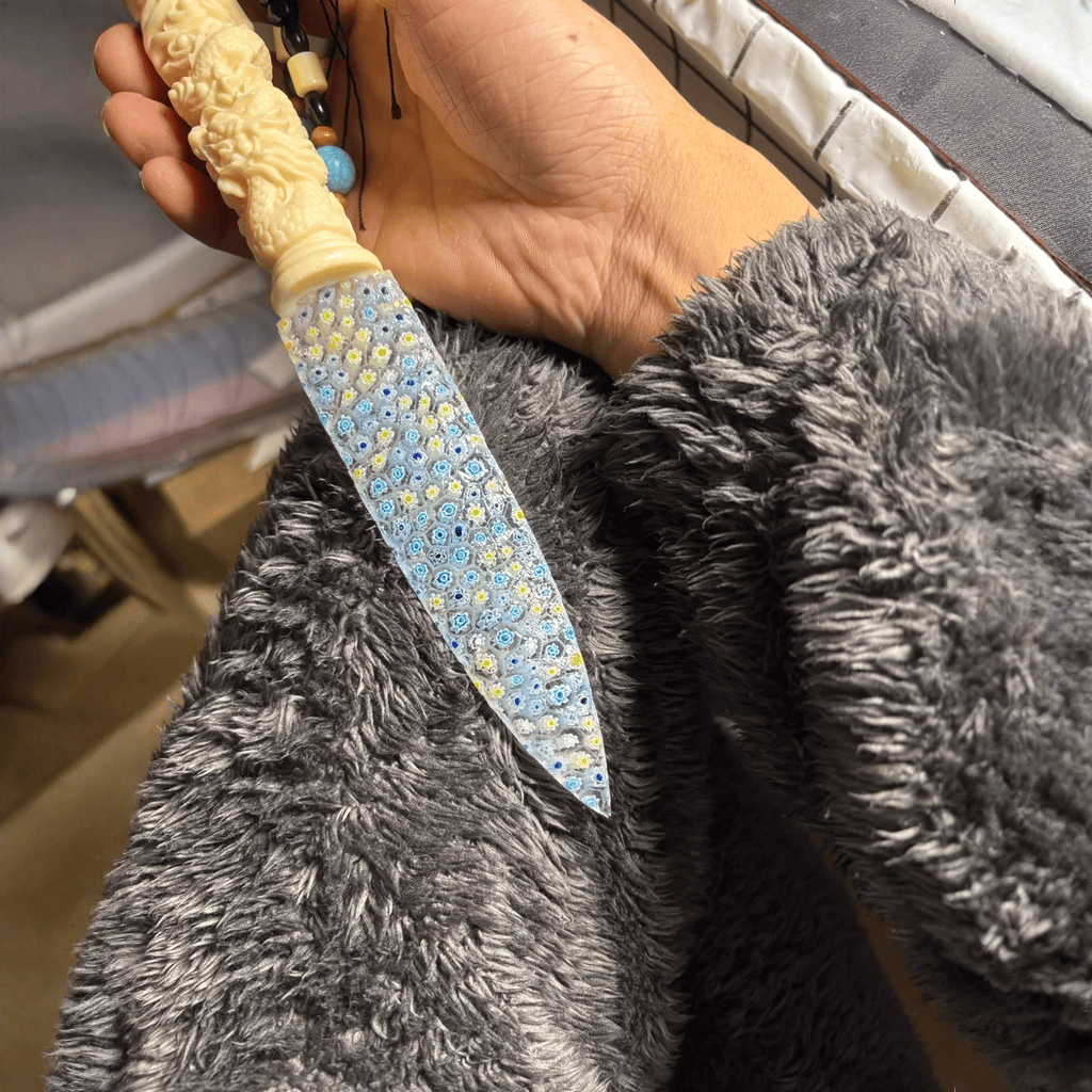 Stoneblade Forge Dagger Stone Blade “Moonrime” — handheld close-up highlighting the multicolor mosaic blade texture and carved handle detail with bead strand.
