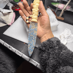 Stoneblade Forge Dagger Stone Blade “Moonrime” — in-hand product shot over a workbench, showing the full mosaic blade, carved ivory-style handle, and decorative bead lanyard.