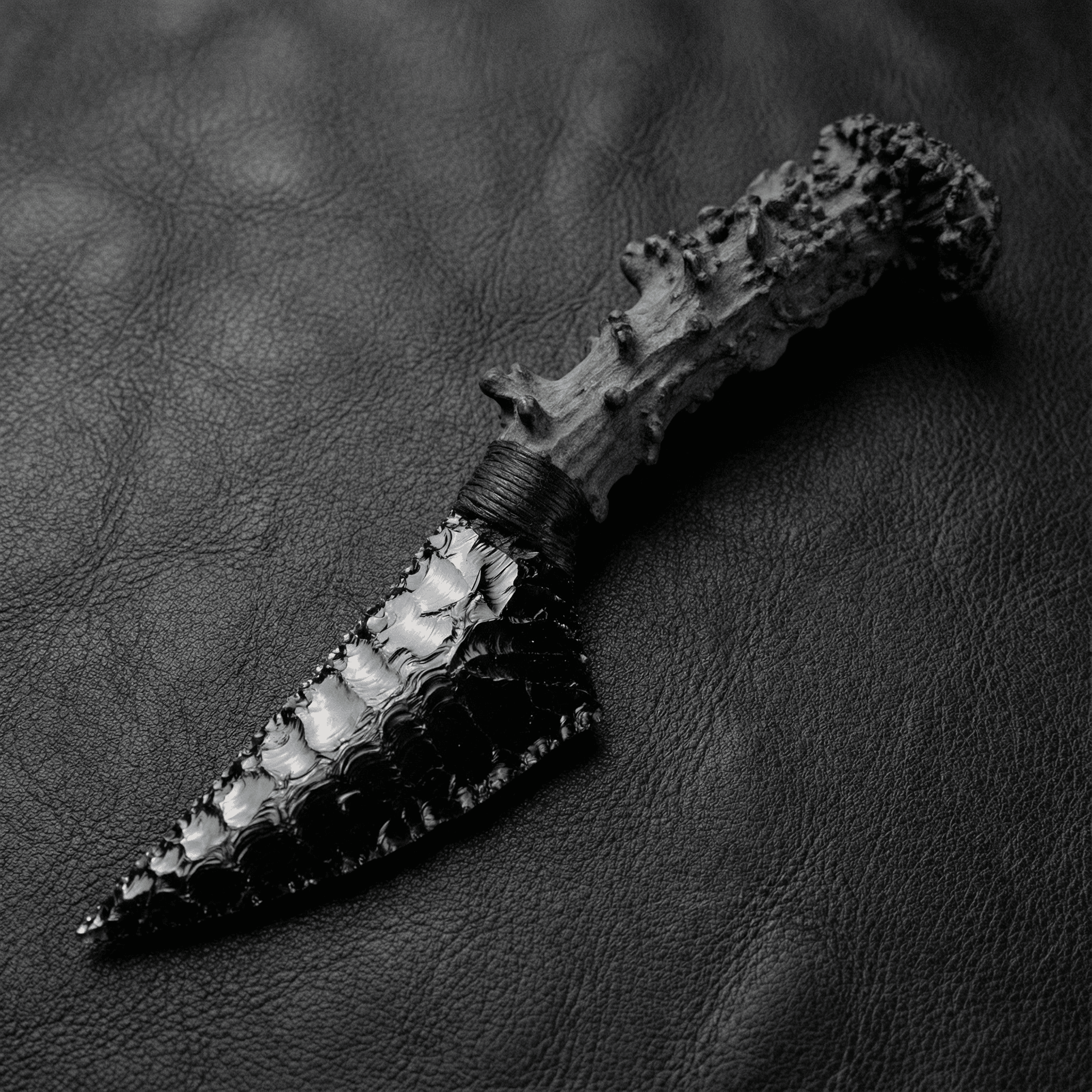 Stoneblade Forge Dagger Stone Blade “Nightfang” — glossy black obsidian-like dagger on black leather, featuring a chunky textured dark handle and cord-wrapped grip.
