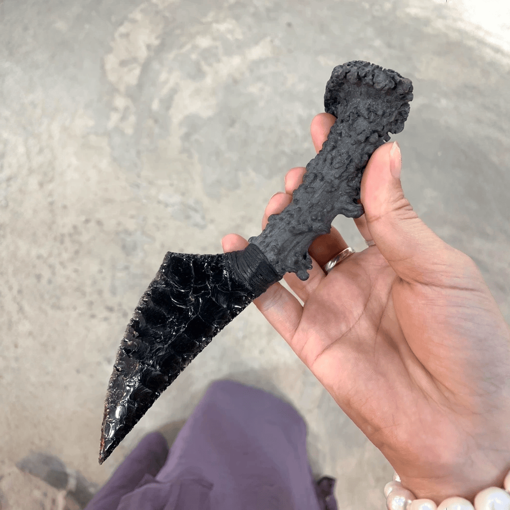 Handheld close-up showing the Nightfang dagger’s textured handle and cord-wrapped grip against a neutral floor background.