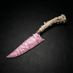Rose-pink stone blade dagger with antler handle on dark leather background