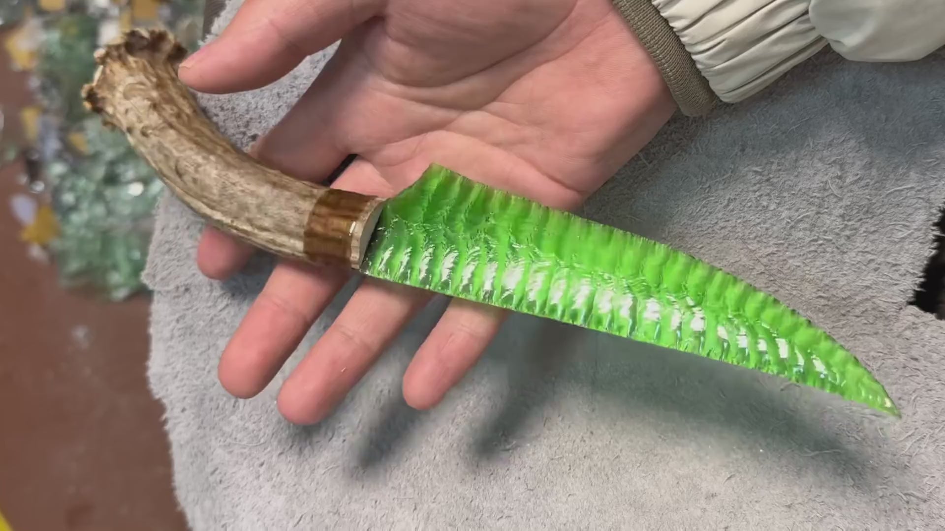 Stoneblade Forge making-process video—hand-knapping a green gemstone stone blade, flaking the material bit by bit to form sharp edges and signature scar patterns in real handcrafted stonework.