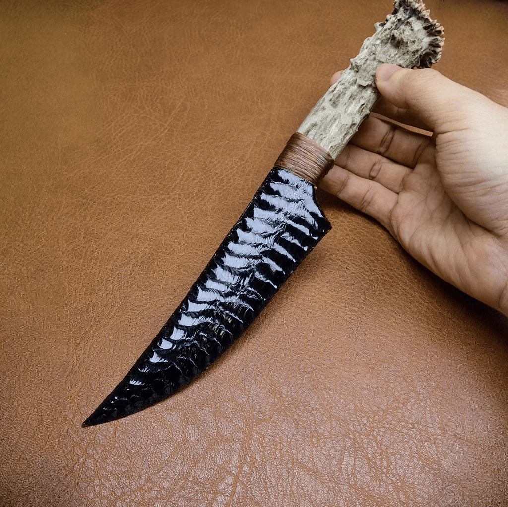 Marauder obsidian crystal stone blade dagger held in hand on brown leather surface, full length view