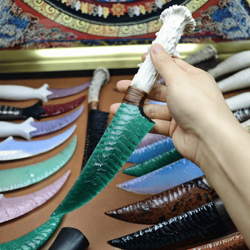 Hand holding Marauder obsidian dagger with antler handle on brown leather surface